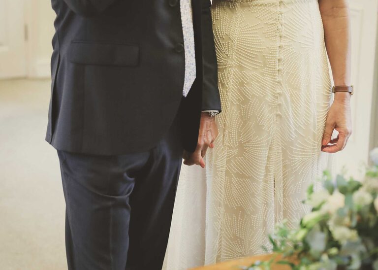 A bride and groom holding hands at a wedding ceremony at Woodbridge Shire Hall photographed by Suffolk Wedding Photographers Hayley Denston Photography