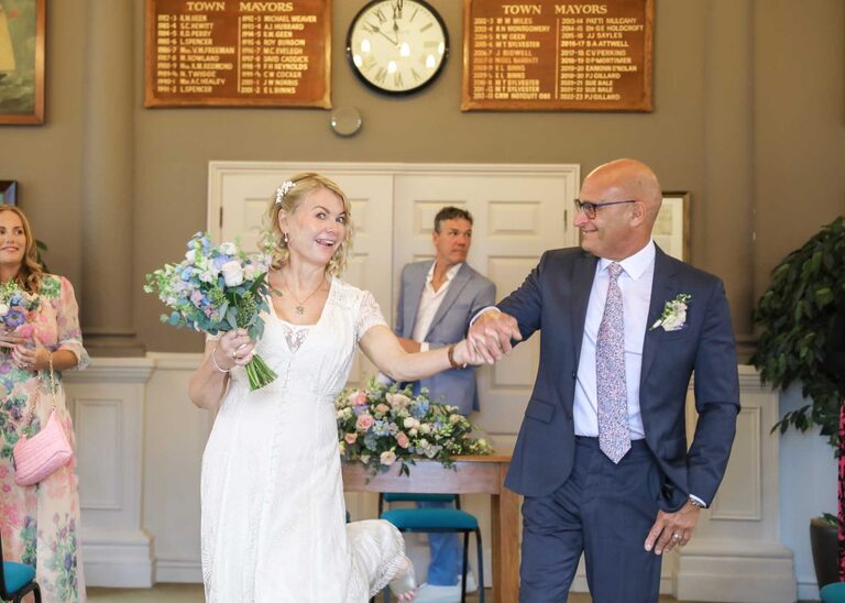 A bride and groom walking out of their wedding ceremony just married on a rainy wedding day at Woodbridge Shire Hall photographed by Suffolk Wedding Photographers Hayley Denston Photography