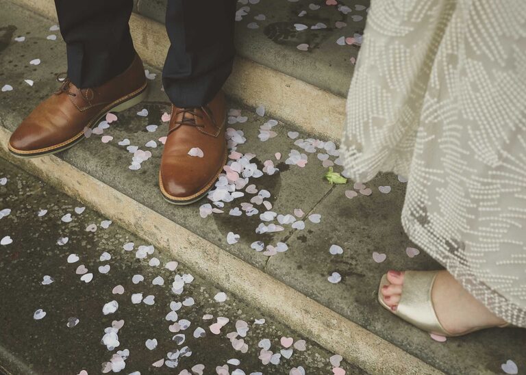 A bride and grooms feet and white and pink heart confetti on a rainy wedding day at Woodbridge Shire Hall photographed by Suffolk Wedding Photographers Hayley Denston Photography