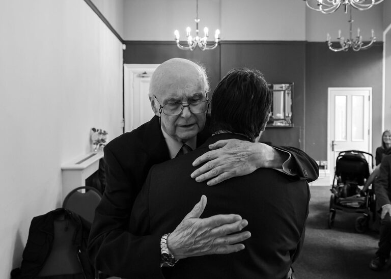 A dad hugging his groom son at Ipswich Town Hall taken by Suffolk Wedding Photographer Hayley Denston Photography