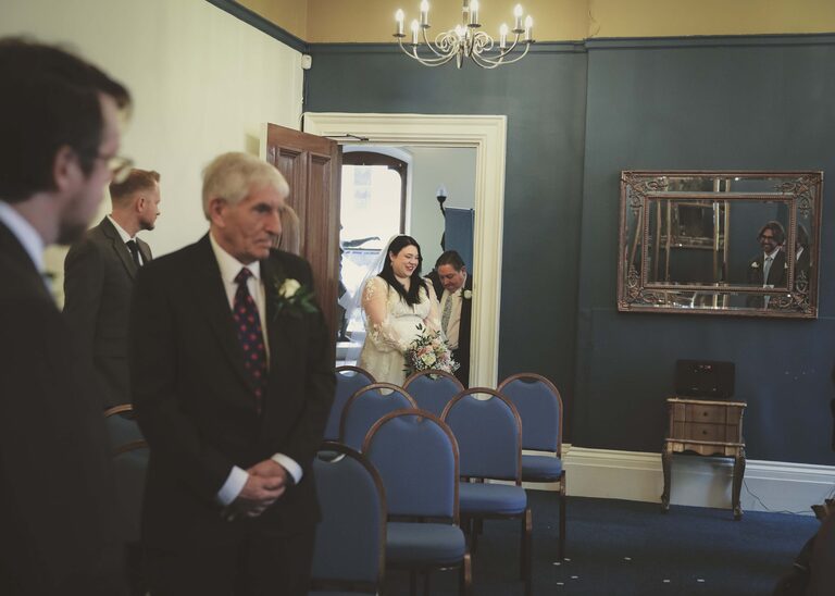 A bride walking up the aisle in the ceremony room at Ipswich Town Hall taken by Suffolk Wedding Photographer Hayley Denston Photography