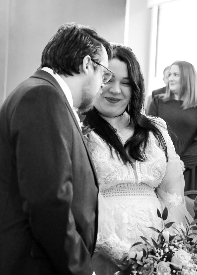 A bride and groom exchanging a look when she reaches the end of the aisle on their wedding day at Ipswich Town Hall taken by Suffolk Wedding Photographer Hayley Denston Photography