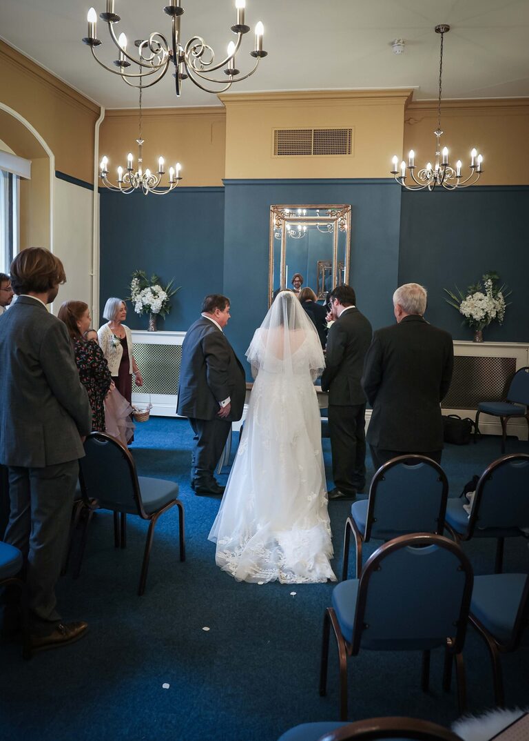 A bride and groom stood from behind in the ceremony room at Ipswich Town Hall taken by Suffolk Wedding Photographer Hayley Denston Photography