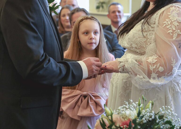 A flowergirl watching her parents exchange their wedding rings during their wedding ceremony at Ipswich Town Hall taken by Suffolk Wedding Photographer Hayley Denston Photography