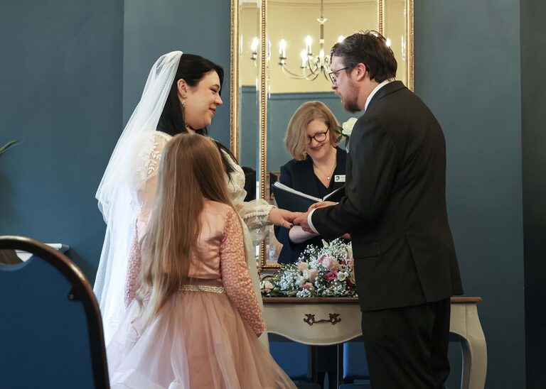 A flowergirl watching her parents exchange their wedding rings at a wedding ceremony at Ipswich Town Hall taken by Suffolk Wedding Photographer Hayley Denston Photography