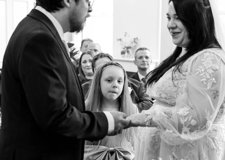 A flowergirl watching her parents exchanging their wedding rings during a wedding ceremony at Ipswich Town Hall taken by Suffolk Wedding Photographer Hayley Denston Photography