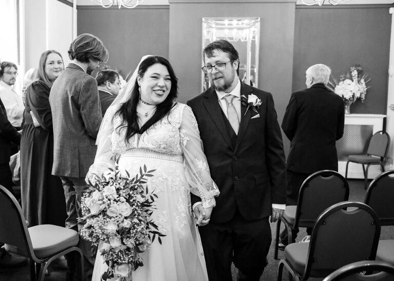 A bride and groom walking out of their wedding ceremony holding hands at Ipswich Town Hall taken by Suffolk Wedding Photographer Hayley Denston Photography