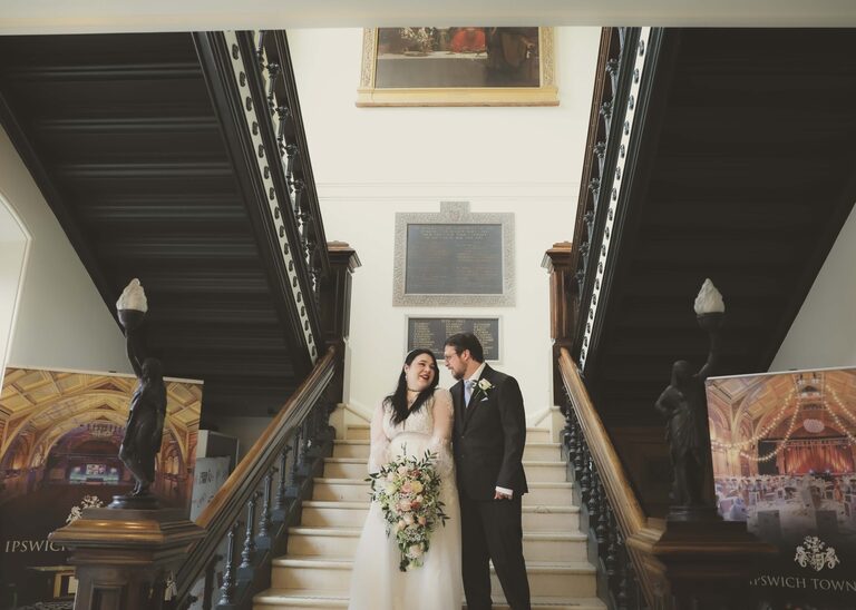 A bride and groom looking at each other on their wedding day on the stairs at Ipswich Town Hall taken by Suffolk Wedding Photographer Hayley Denston Photography