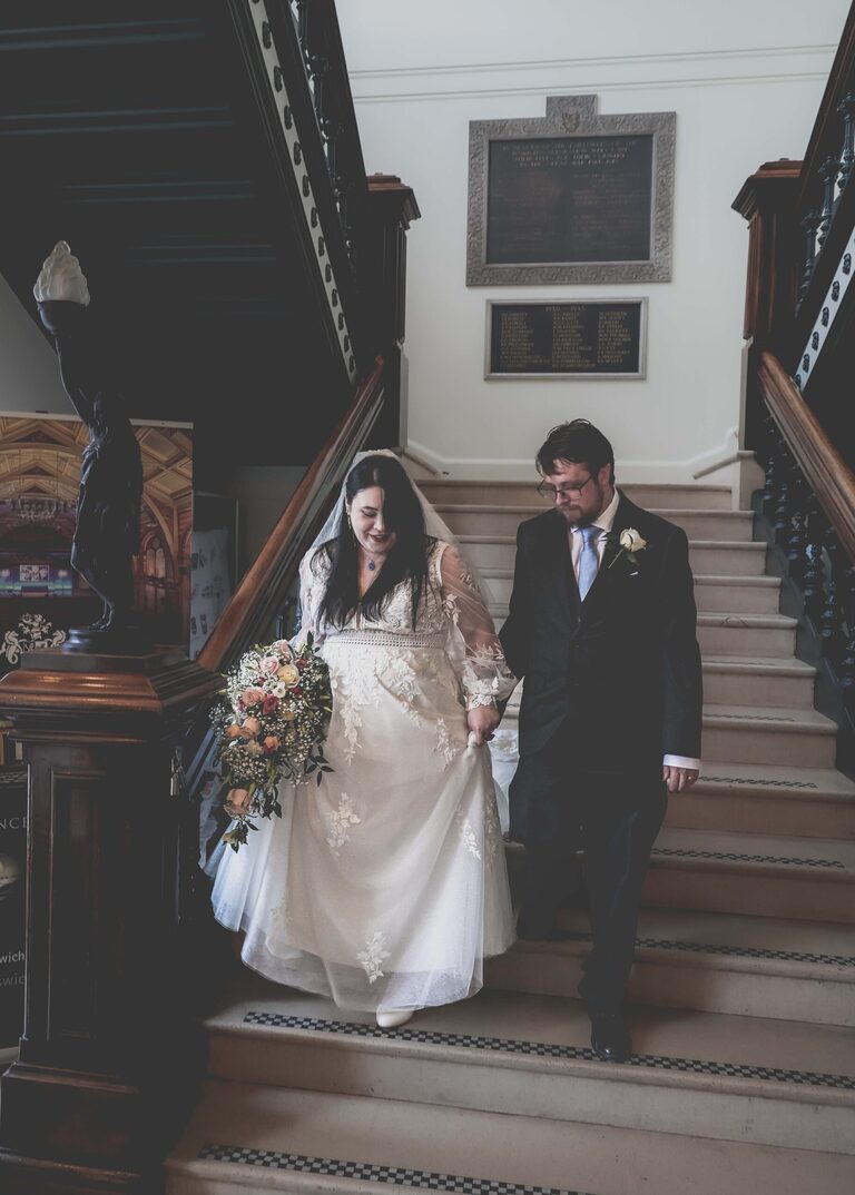 A bride and groom walking down the stairs on their wedding day at Ipswich Town Hall taken by Suffolk Wedding Photographer Hayley Denston Photography