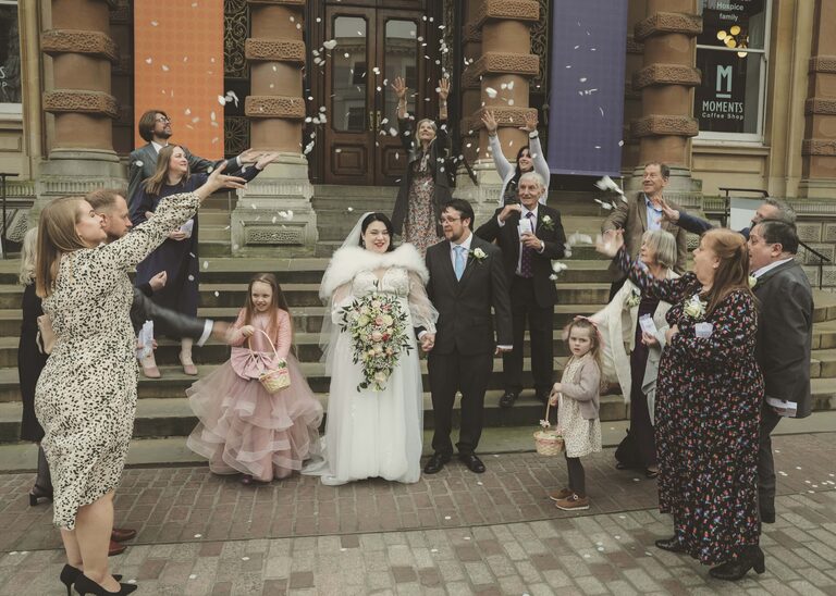 A bride and groom being covered in confetti by guests at Ipswich Town Hall taken by Suffolk Wedding Photographer Hayley Denston Photography
