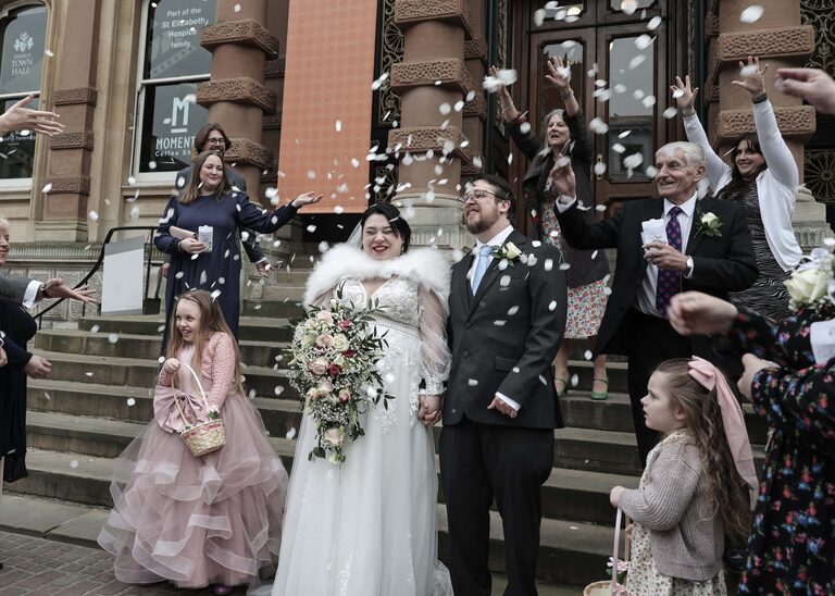 A bride and groom being covered in confetti by guests at Ipswich Town Hall taken by Suffolk Wedding Photographer Hayley Denston Photography