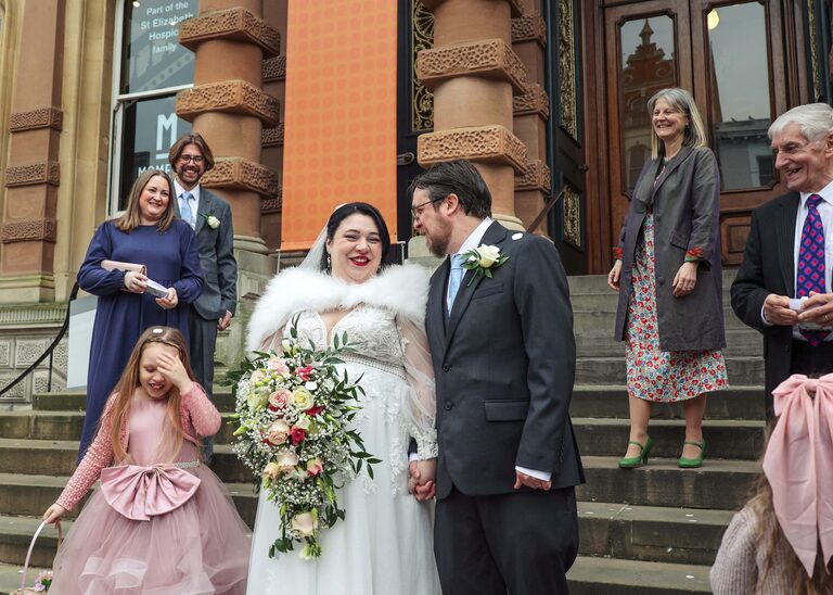 A bride and groom smiling at each other after being covered in confetti by guests at Ipswich Town Hall taken by Suffolk Wedding Photographer Hayley Denston Photography