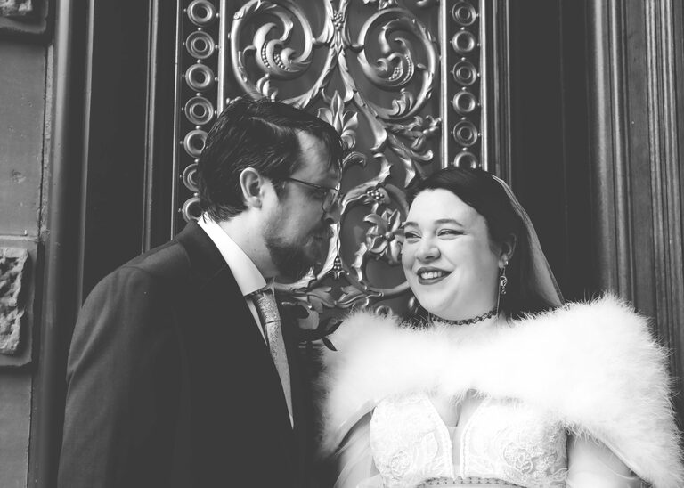A black and white photo of a bride and groom smiling at each other on their wedding day at Ipswich Town Hall taken by Suffolk Wedding Photographer Hayley Denston Photography