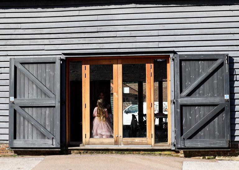 A flowergirl in black barn on a wedding day taken by Suffolk Wedding Photographer Hayley Denston Photography