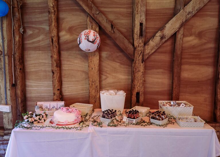 Cake and nibbles set up in the Tithe Barn Sproughton on a wedding day taken by Suffolk Wedding Photographer Hayley Denston Photography