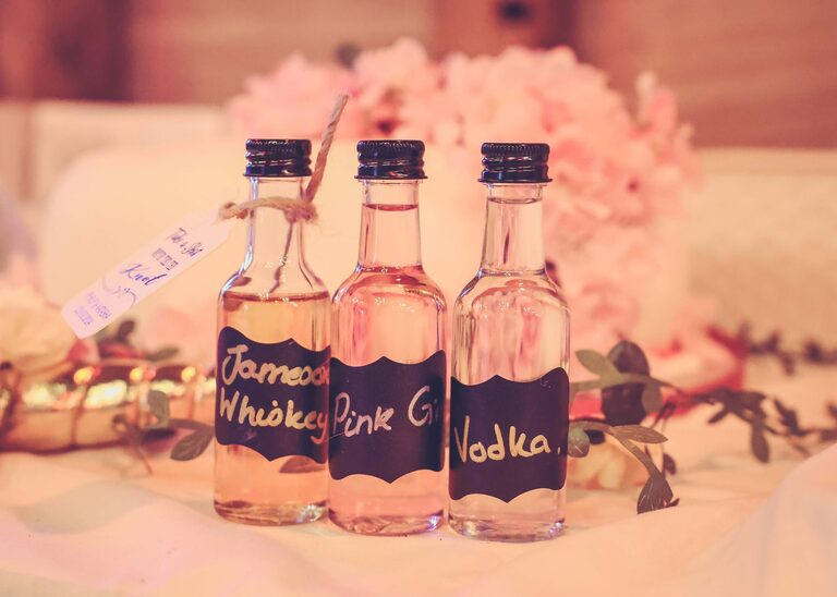 Wedding favours that are small bottles of alcohol in the Tithe Barn Sproughton on a wedding day taken by Suffolk Wedding Photographer Hayley Denston Photography