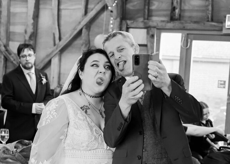 A bride and her brother in law pulling silly faces for a selfie at the Tithe Barn Sproughton on a wedding day taken by Suffolk Wedding Photographer Hayley Denston Photography