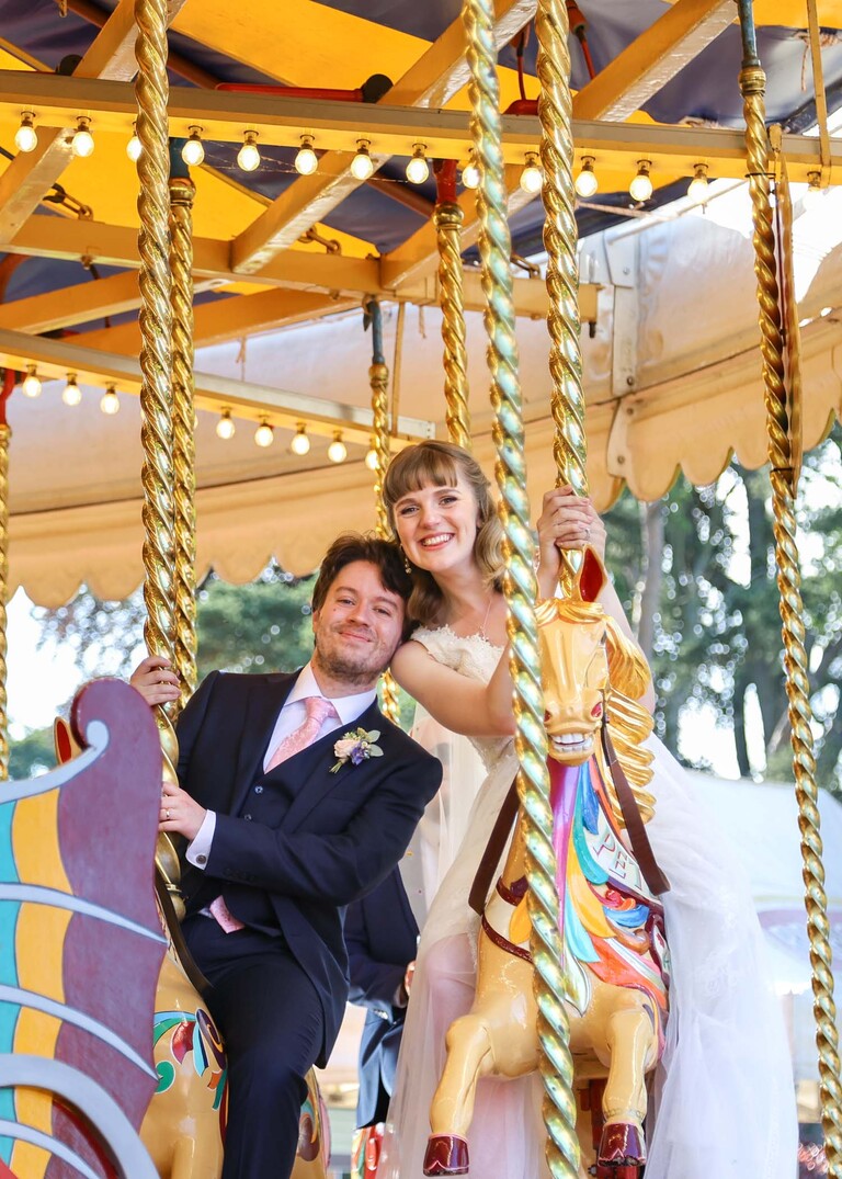 A bride and groom on the gallopers on a wedding day at Bressingham Hall and High Barn captured by Suffolk Wedding Photographers Hayley Denston Photography