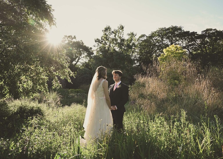 A bride and groom stood in Bressingham Gardens during golden hour on a wedding day at Bressingham Hall and High Barn captured by Suffolk Wedding Photographers Hayley Denston Photography