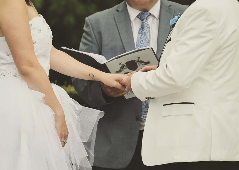A ring exchange and a close up of hands  during their outdoor wedding ceremony on a wedding day at Swynford Manor in Suffolk Captured by Suffolk Wedding Photographer Hayley Denston Photography