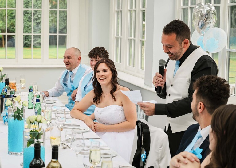 A groom giving his speech and the bride laughing on a wedding day at Swynford Manor in Suffolk Captured by Suffolk Wedding Photographer Hayley Denston Photography