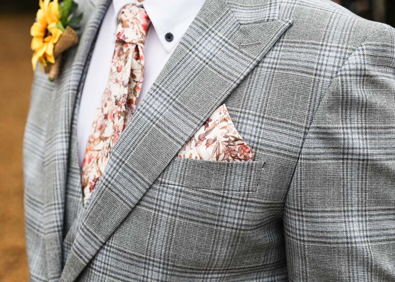 A pink floral handkerchied and tie against a grey check suit on a wedding day at the Garden Barn, Little Bradley captured by Hayley Denston Photography