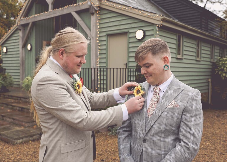 A bestman putting on the grooms buttonhole on a wedding day at the Garden Barn, Little Bradley captured by Hayley Denston Photography