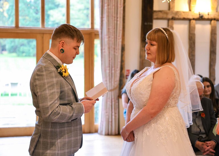 A groom reading his personalised vows to the bride during their wedding ceremony on a wedding day at the Garden Barn, Little Bradley captured by Hayley Denston Photography