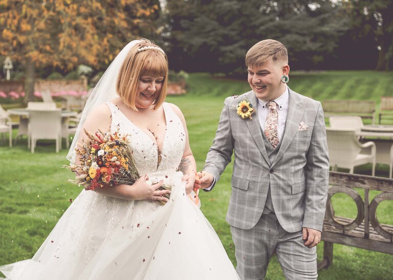 A groom helping a bride remove some confetti from her dress on a wedding day at the Garden Barn, Little Bradley captured by Hayley Denston Photography