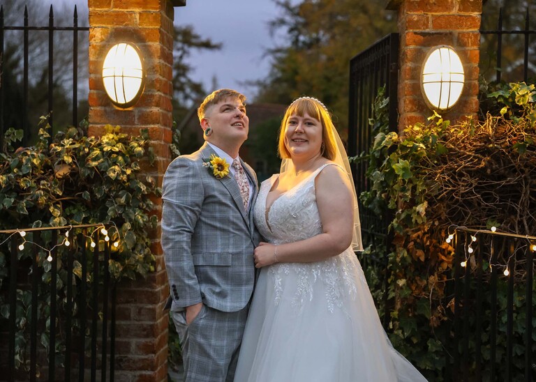 A groom looking up at birds going over at dusk with his bride cuddling him on their wedding day at the Garden Barn, Little Bradley captured by Hayley Denston Photography