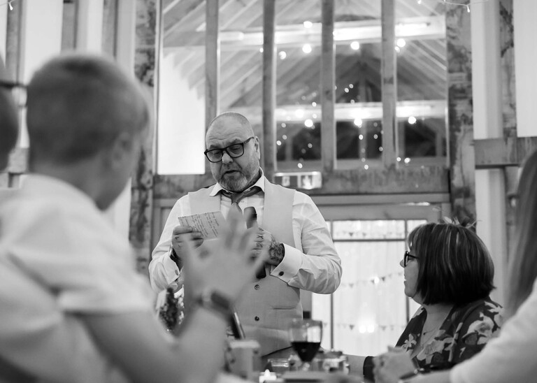 A black and white photo of the father of the bride giving a wedding speech on a wedding day at the Garden Barn, Little Bradley captured by Hayley Denston Photography