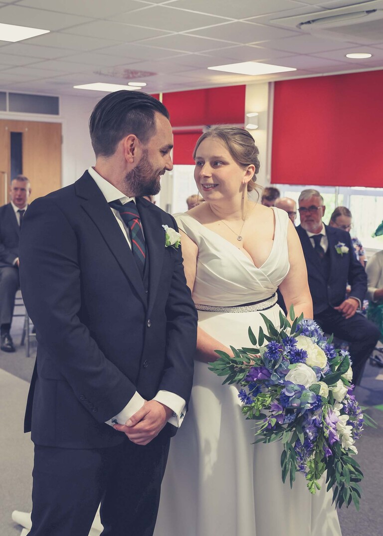 A bride and groom looking at each other during their wedding ceremony at Cambridge Registry Office photographed by Suffolk Wedding Photographer Hayley Denston Photography