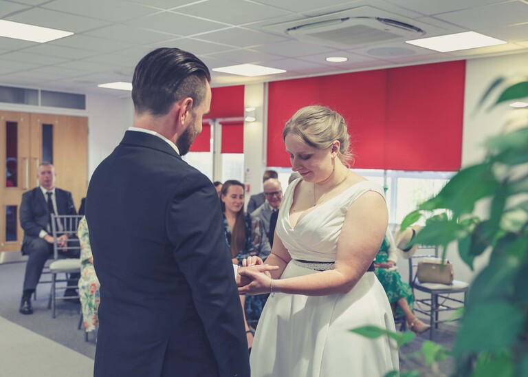 A bride and groom exchanging rings during their wedding ceremony at Cambridge Registry Office photographed by Suffolk Wedding Photographer Hayley Denston Photography