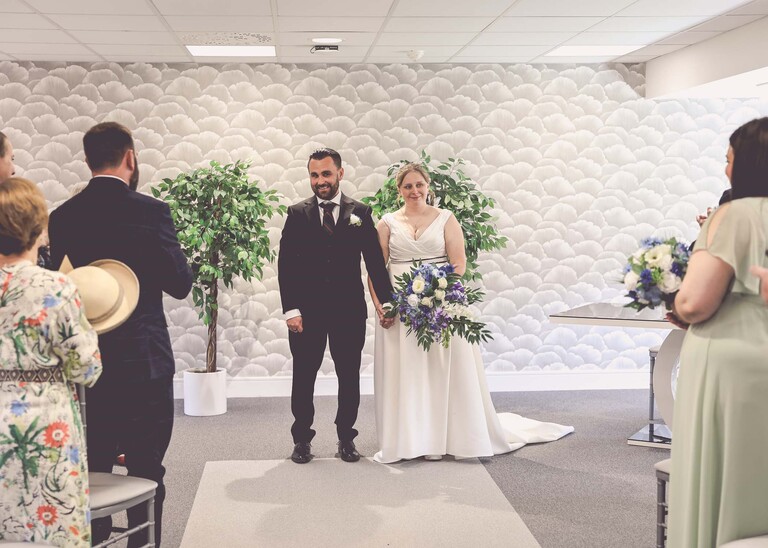 A bride and groom facing their guests during their wedding ceremony at Cambridge Registry Office photographed by Suffolk Wedding Photographer Hayley Denston Photography