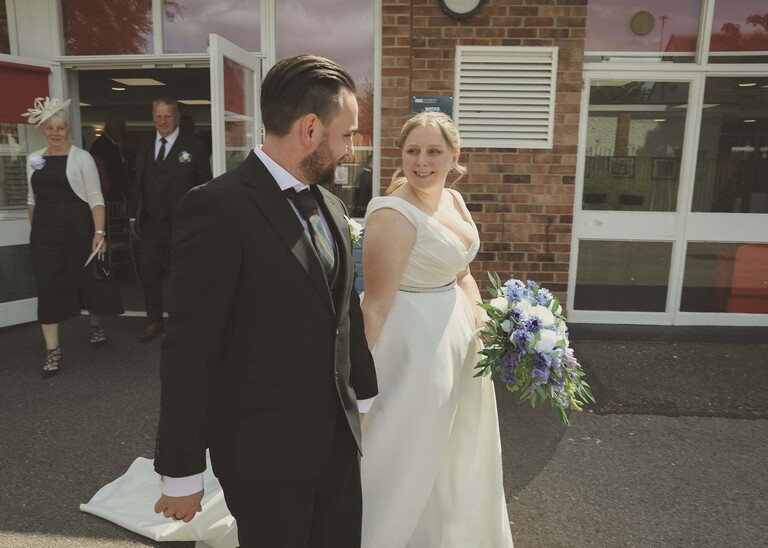 A bride and groom walking out after a wedding ceremony at Cambridge Registry Office photographed by Suffolk Wedding Photographer Hayley Denston Photography
