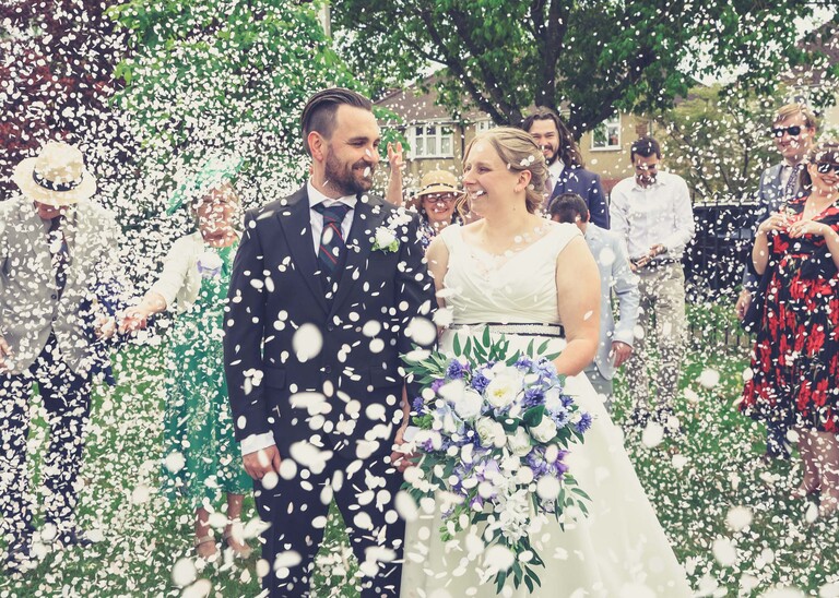 A bride and groom covered with lots of confetti at Cambridge Registry Office  photographed by Suffolk Wedding Photographer Hayley Denston Photography