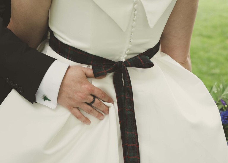 A groom with his hand on his brides bottom and you can see her tartan ribbon around her dress on their wedding day photographed by Suffolk Wedding Photographer Hayley Denston Photography
