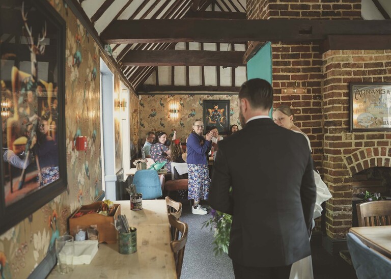 A bride and groom walking in to their wedding reception at the castle inn in Cambridge photographed by Suffolk Wedding Photographer Hayley Denston Photography