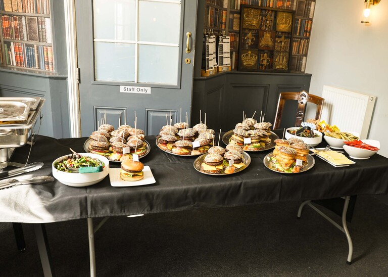 A table with burgers, fries and condiments laid out for a wedding breakfast at The Castle Inn in Cambridge photographed by Suffolk Wedding Photographer Hayley Denston Photography