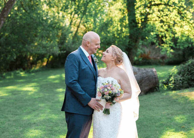 A bride and groom looking at each other with trees and the dappled sun coming through at sunset on their wedding day at The White Hart Great Yeldham photographed by Suffolk Wedding Photographer Hayley Denston Photography