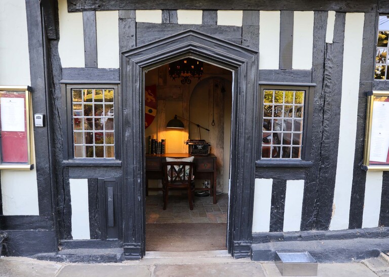 The entrance to the White Hart on a wedding day where you can see a lamp and an old typewriter through the tudor door photographed by Suffolk Wedding Photographer Hayley Denston Photography