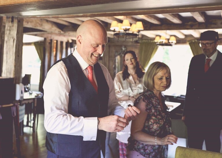 A groom putting on his cufflinks at his wedding day at The White Hart Great Yeldham photographed by Suffolk Wedding Photographer Hayley Denston Photography