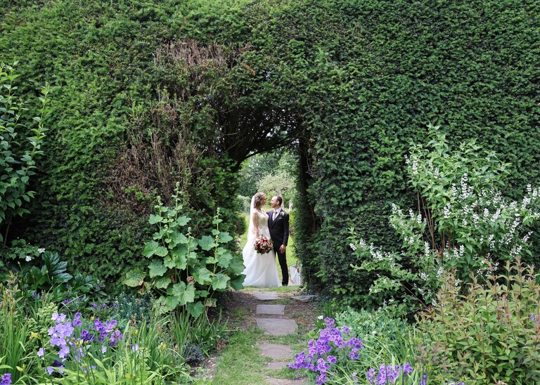 A bride and groom in a hedge archway at Hintlesham Hall on a wedding day captured by Suffolk Wedding Photographer Hayley Denston Photography