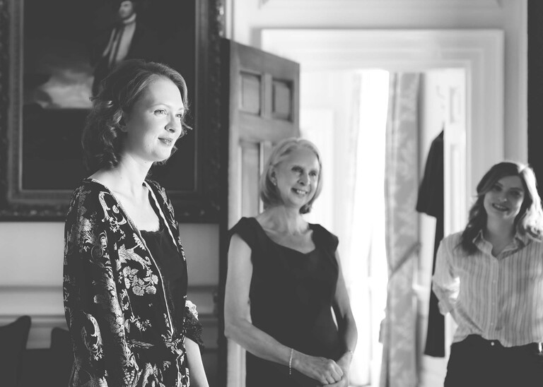 A black and white photo of a bride, her mum and her bestfriend getting ready at Hintlesham Hall on a wedding day captured by Suffolk Wedding Photographer Hayley Denston Photography