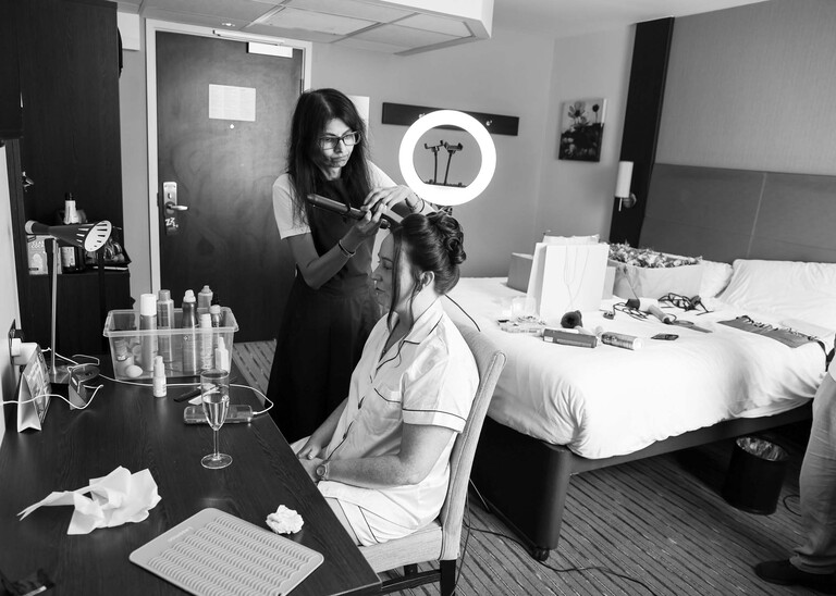 A black and white photo of a bride having her hair done on a wedding day captured by suffolk wedding Photographer Hayley Denston Photography