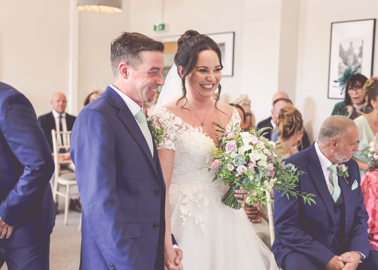 A bride and groom smiling during their wedding ceremony at bury st edmunds registry office on a wedding day captured by suffolk wedding photographer Hayley Denston Photography