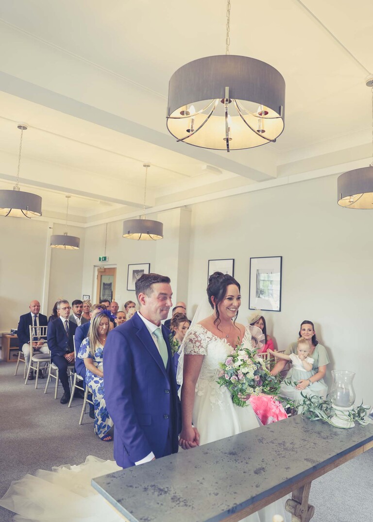 A bride and groom stood at the front during their wedding ceremony at bury st edmunds registry office on a wedding day captured by suffolk wedding photographer Hayley Denston Photography