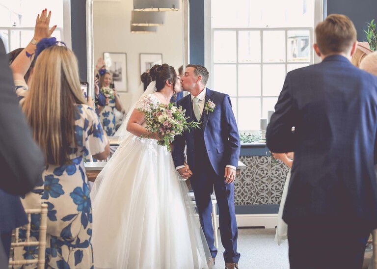 A bride and groom kissing before they are about to walk down the aisle after their wedding ceremony at bury st edmunds registry office on a wedding day captured by suffolk wedding photographer Hayley Denston Photography