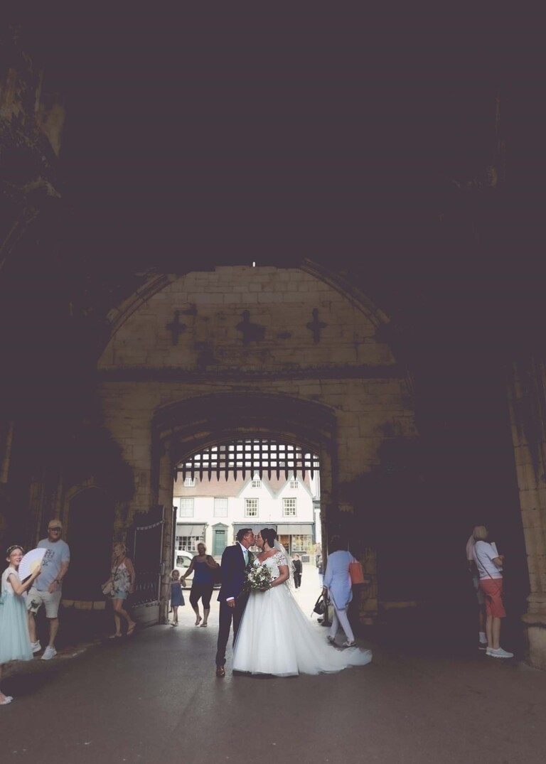 A bride and groom kissing in the gated entrance to bury st edmunds abbey gardens on a wedding day captured by suffolk wedding photographer Hayley Denston Photography