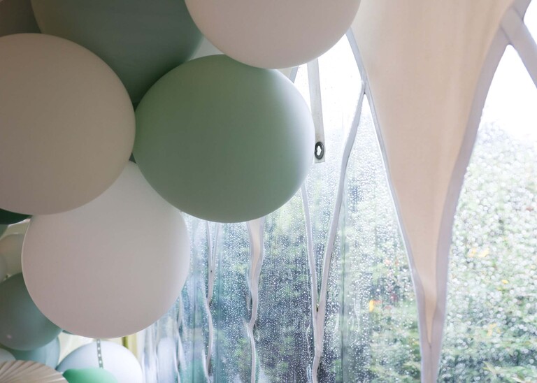 The windows of a marquee and balloons with rain all on the marquee on a wedding day at Hungarian Hall Estate captured by Suffolk Wedding Photographer Hayley Denston Photography